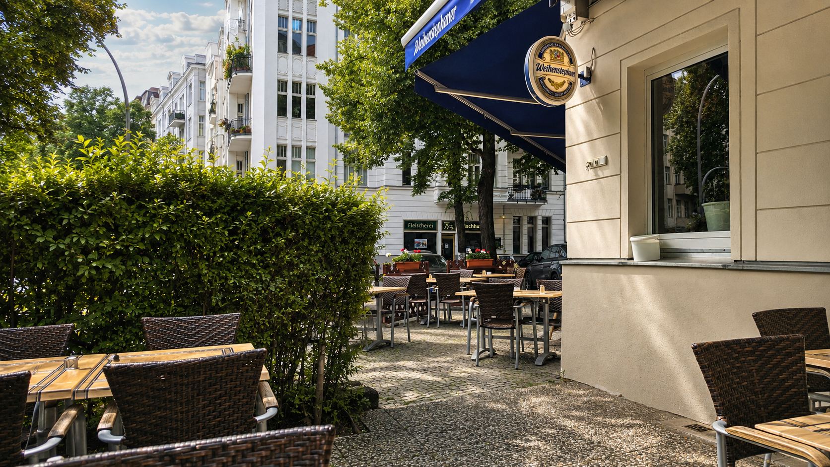 Die Terrasse der Taverna Hellas an der Güntzelstraße mit Tischen unter der Markise.